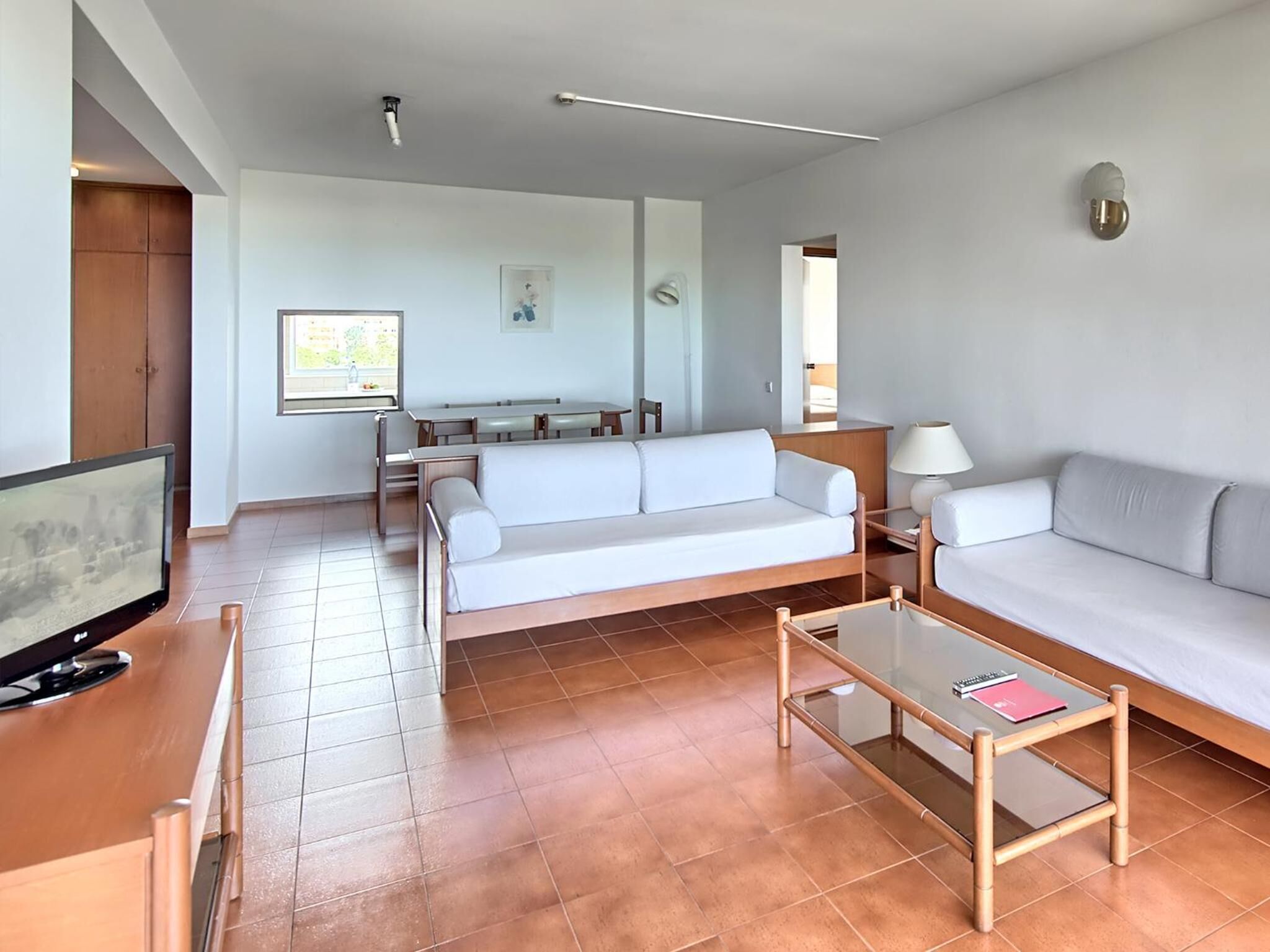 A modern living room with a sofa, a coffee table, a TV, and a dining area.