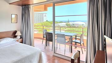 A hotel room with a bed, a desk, and a view of a casino and greenery.