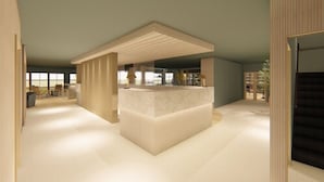 Un intérieur moderne avec un comptoir d’accueil central, un plafond haut et une vue sur l’extérieur grâce à de grandes fenêtres.