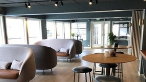Un intérieur moderne avec une table ronde en bois, deux tabourets de bar et deux canapés avec des coussins.