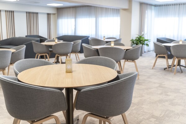 A modern conference room with round tables and grey chairs, featuring a wooden table with a decorative centerpiece.
