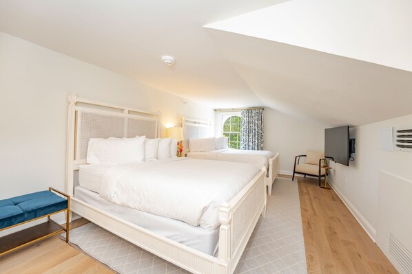 A bedroom with a large bed, a bedside table, a chair, a TV, and a window with curtains.
