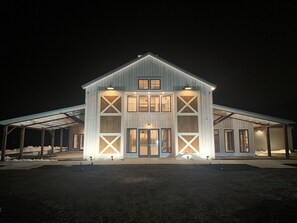 A large, two-story barn-style building with a covered front porch and a garage.