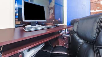 Een houten bureau met een computeropstelling, inclusief een beeldscherm, toetsenbord en muis.