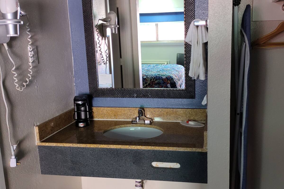 Une salle de bain avec un lavabo, un miroir et un porte-serviettes.