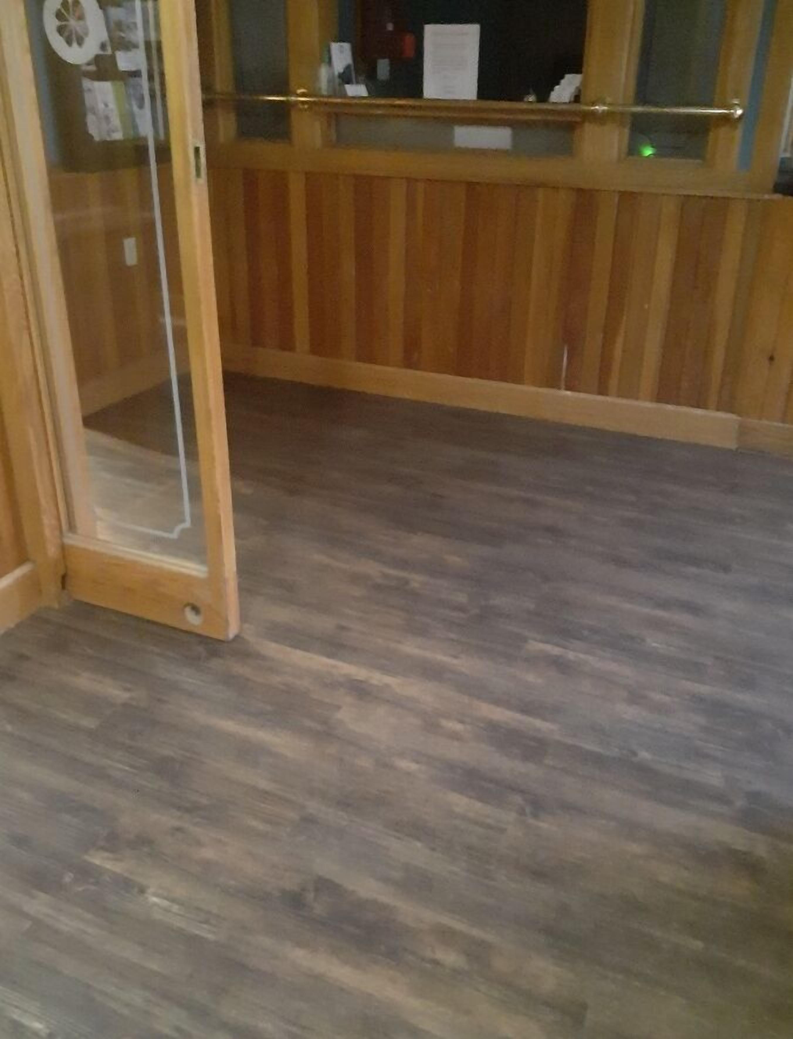 A room with wooden paneling, a glass door, and a wooden floor.