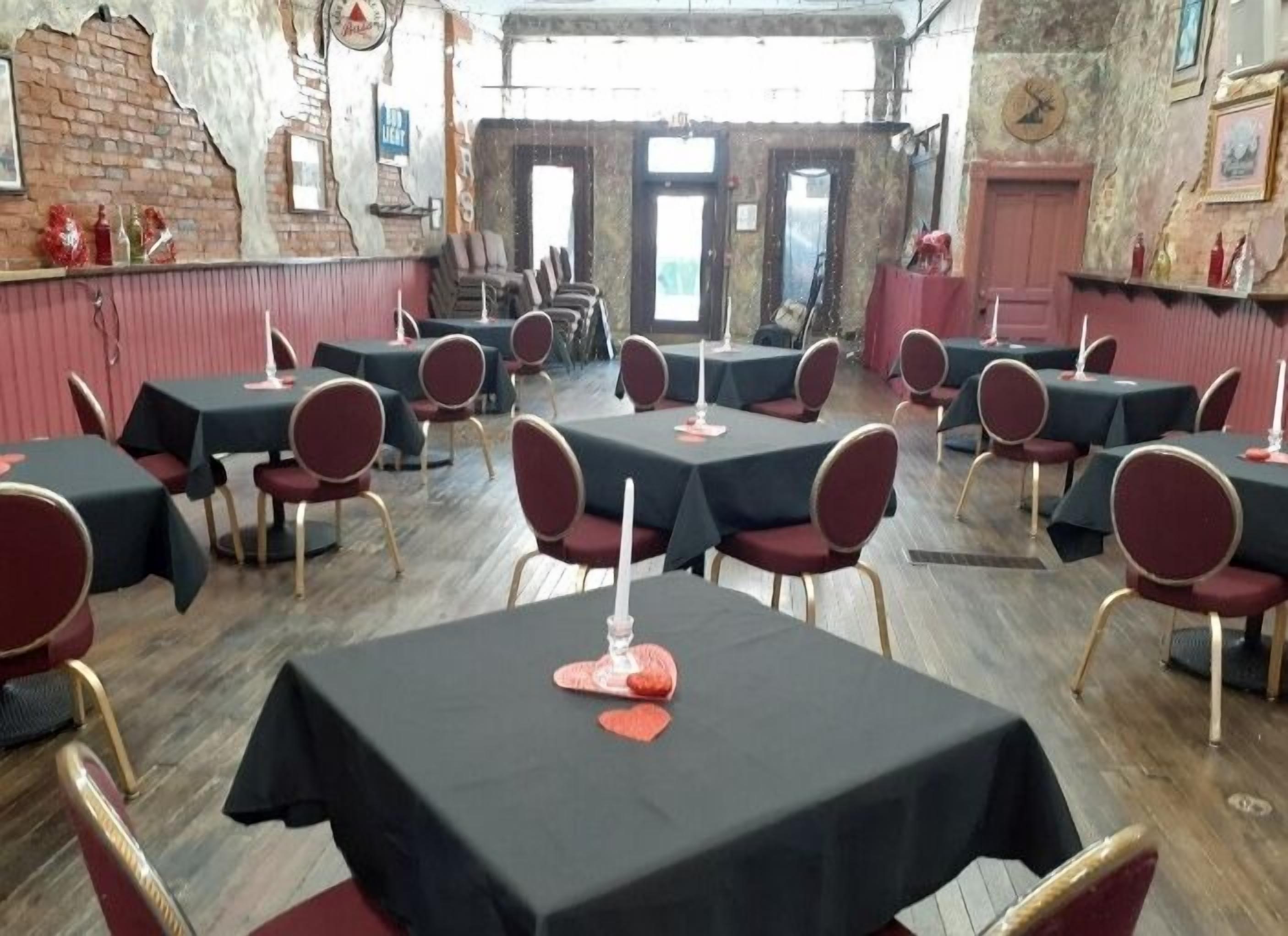 Un restaurante con varias mesas y sillas, una pared de ladrillo y un reloj en la pared.