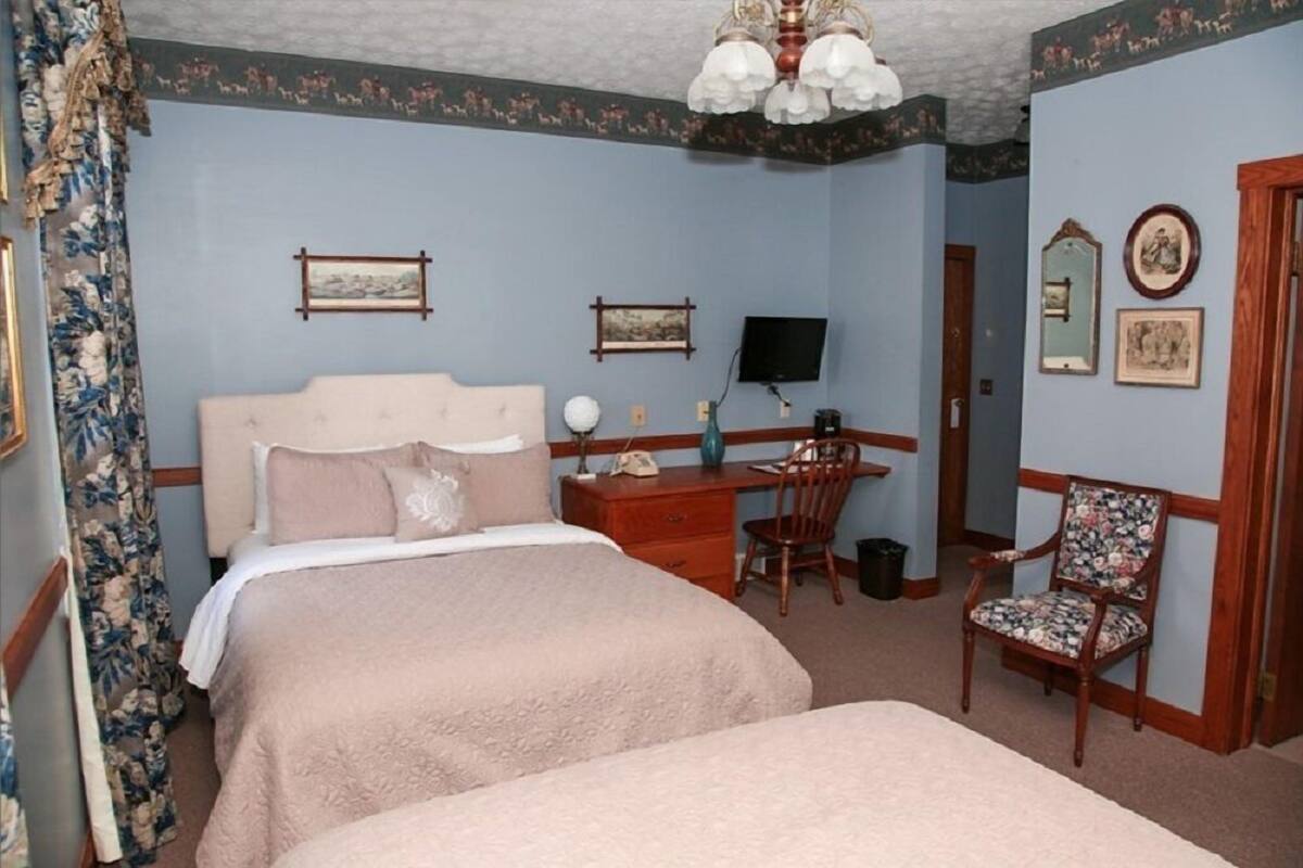 Ein Schlafzimmer mit Doppelbett, Schreibtisch, Stuhl und Fernseher.