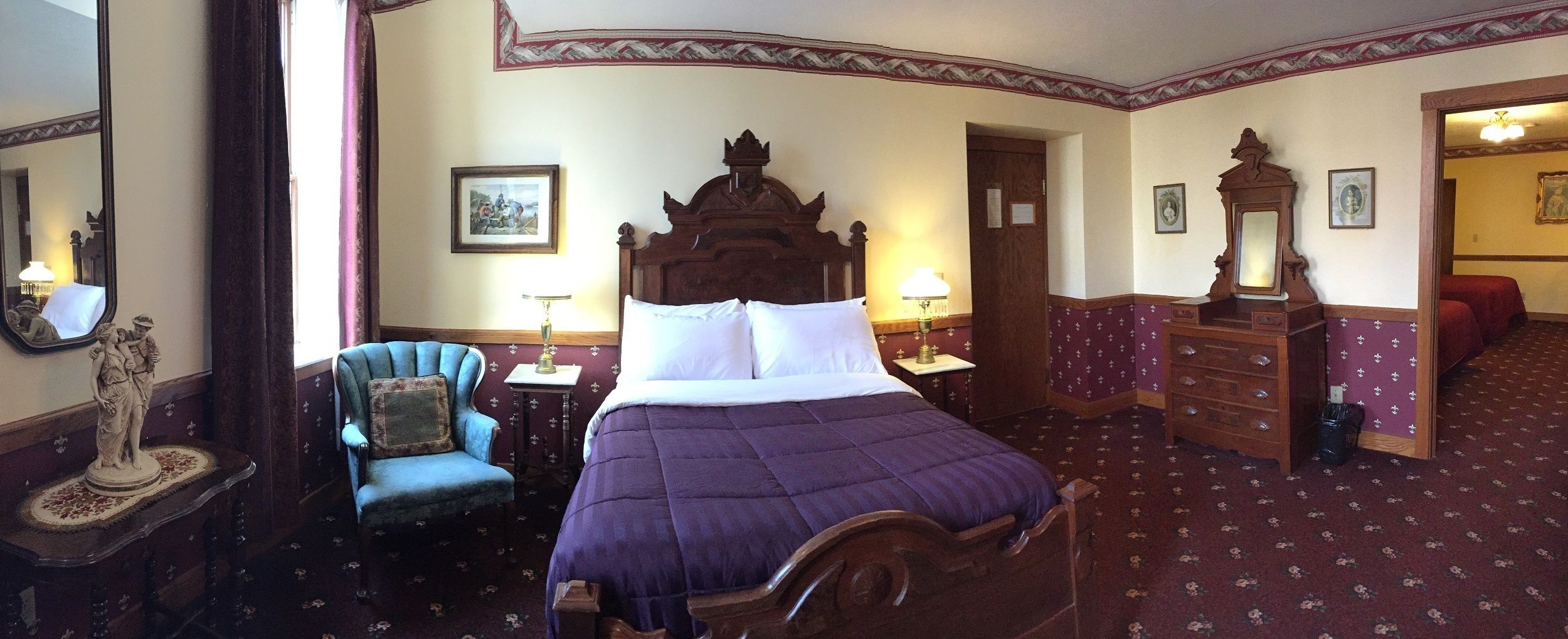 A traditional room with a large bed, a chair, a dresser, and a mirror.