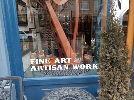 Un escaparate con un letrero que dice "FINE ART and ARTISAN WORK".