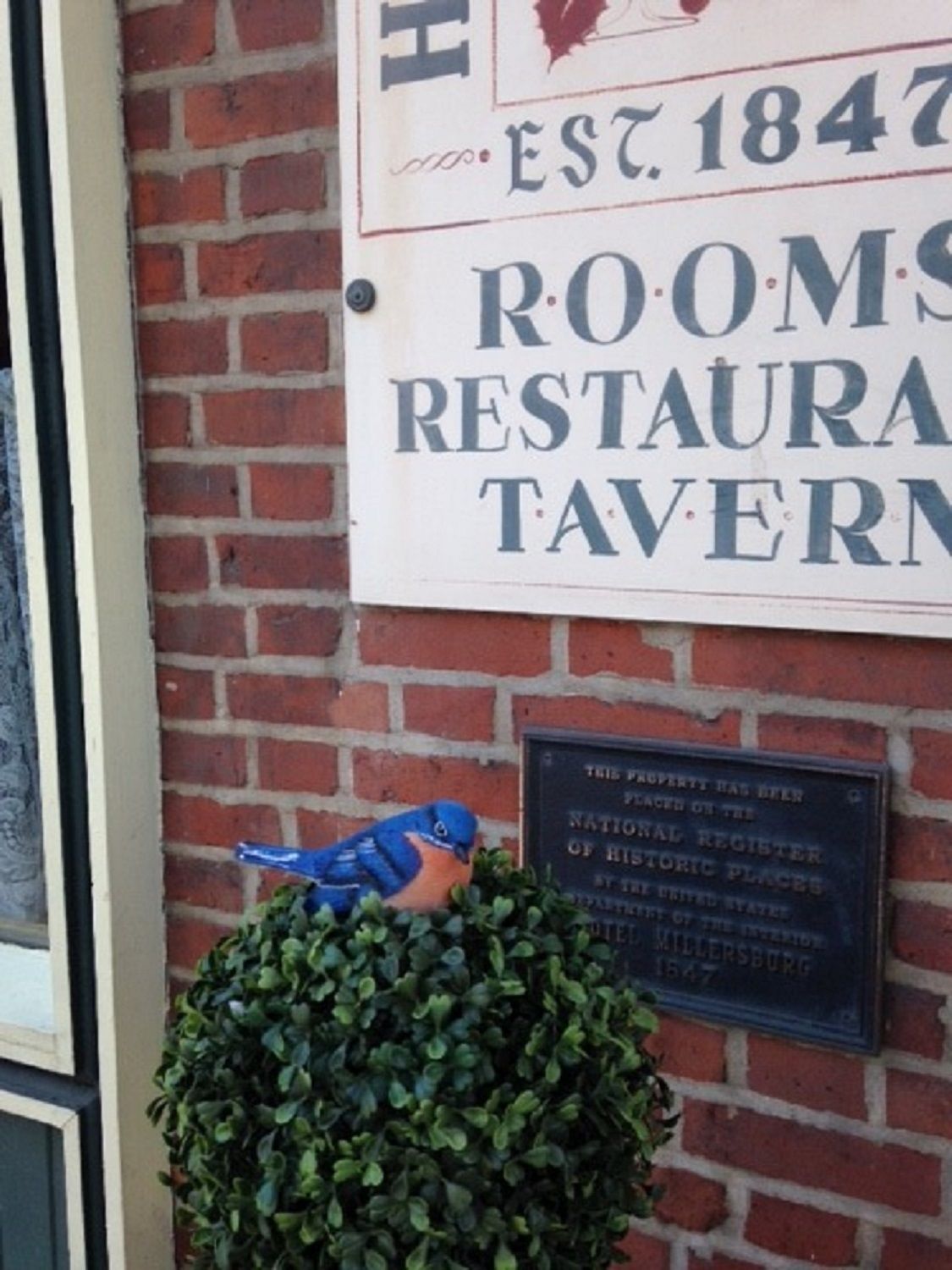 A brick wall with a sign for the Rooms Restaurant Tavern, established in 1847.