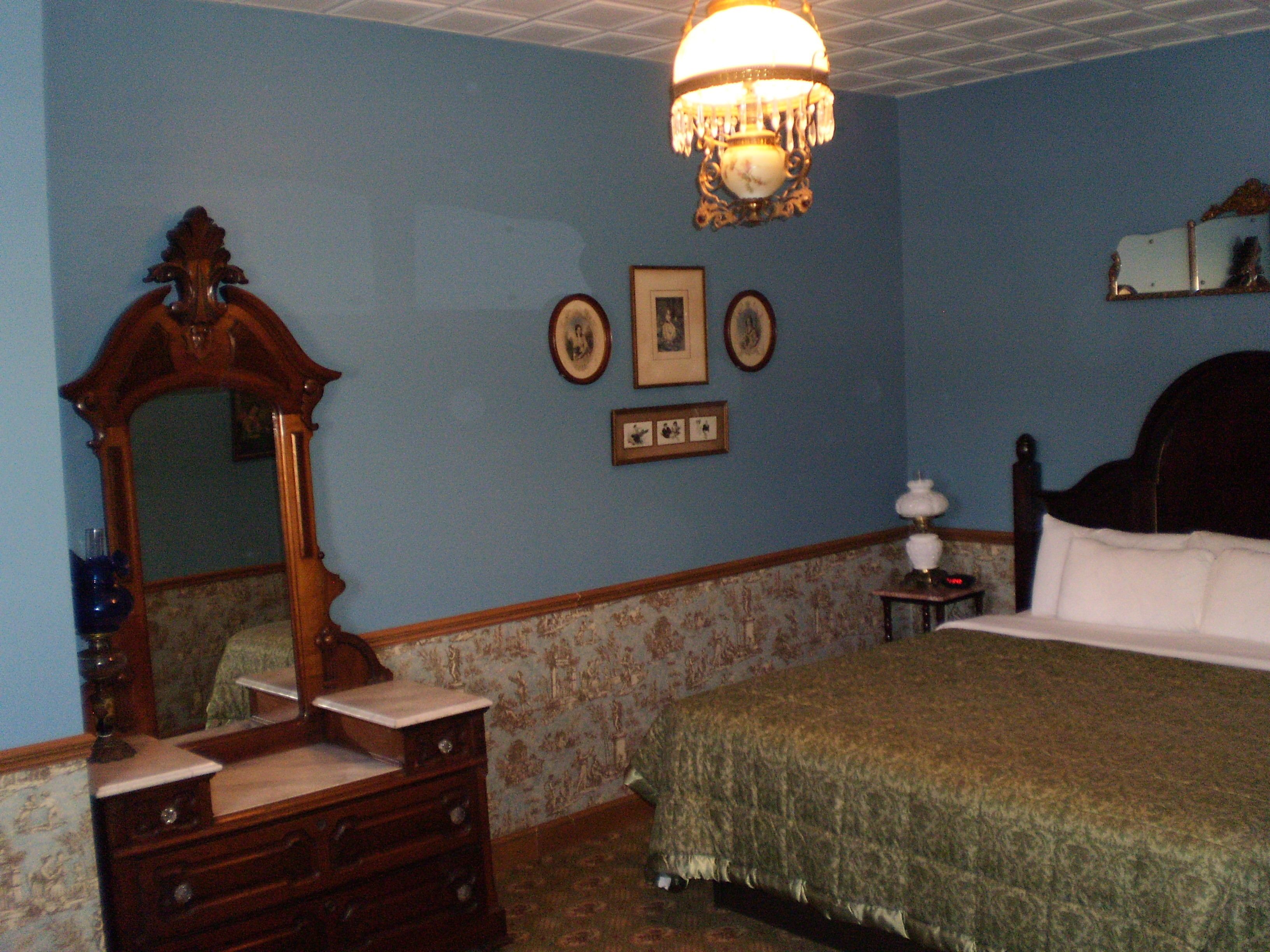 Un dormitorio con una cama grande, un aparador, un espejo y una araña.