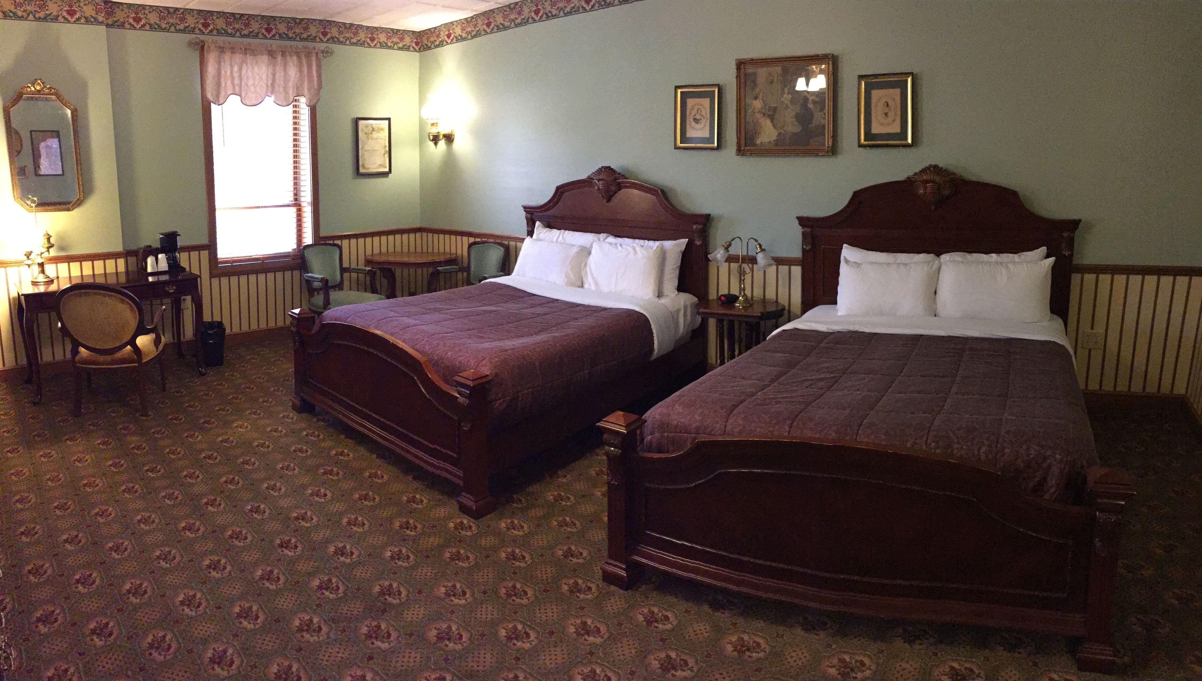 A traditional room with two wooden beds, a desk, a chair, and a small table.