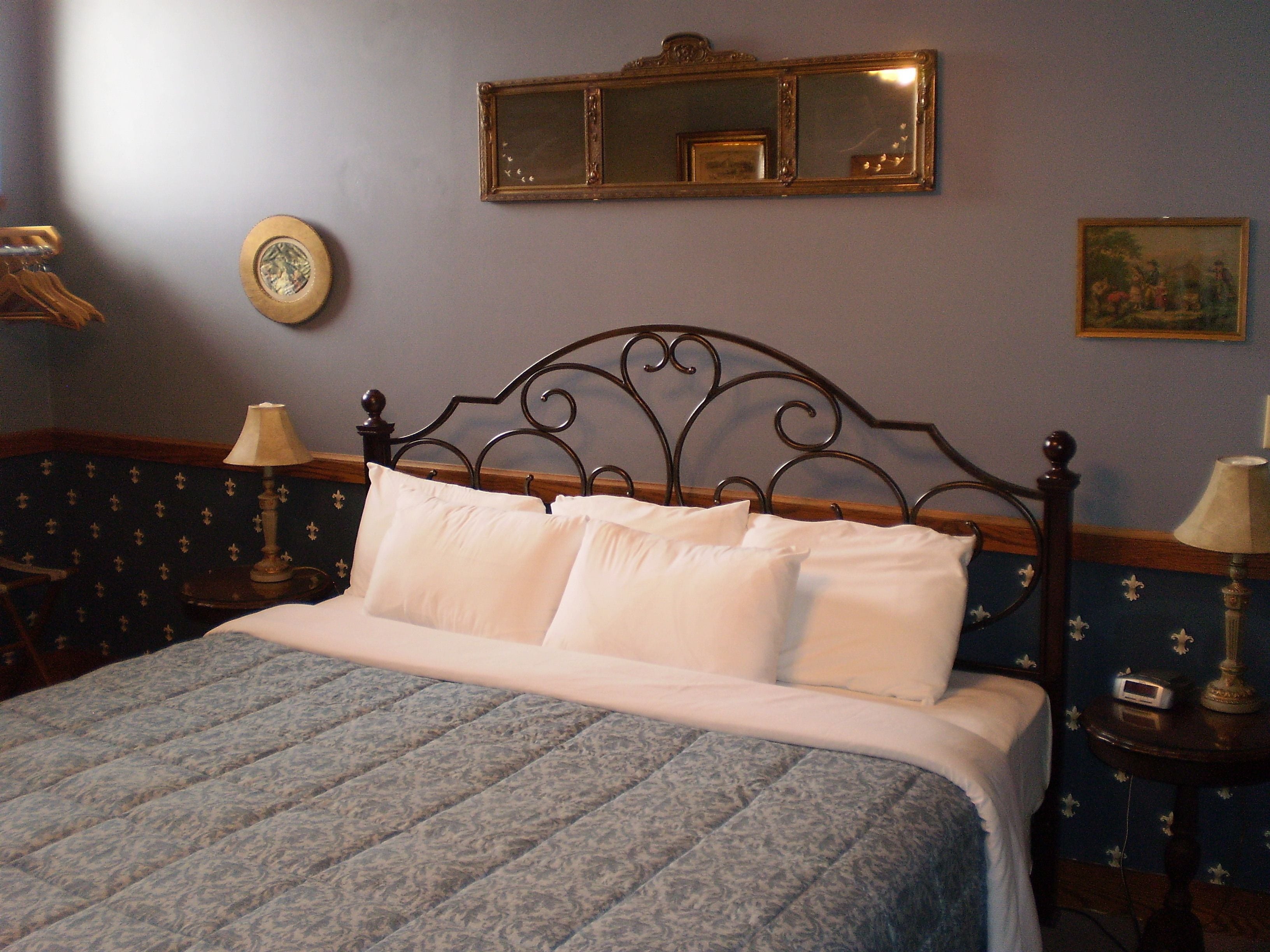 A neatly made bed with a patterned bedspread, a wooden headboard, and two bedside tables with lamps.