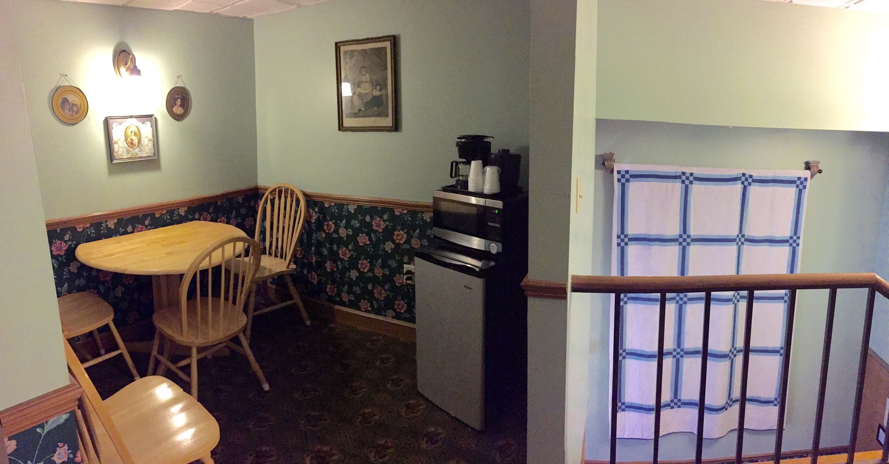 A compact kitchen with a dining area, a refrigerator, and a coffee maker.