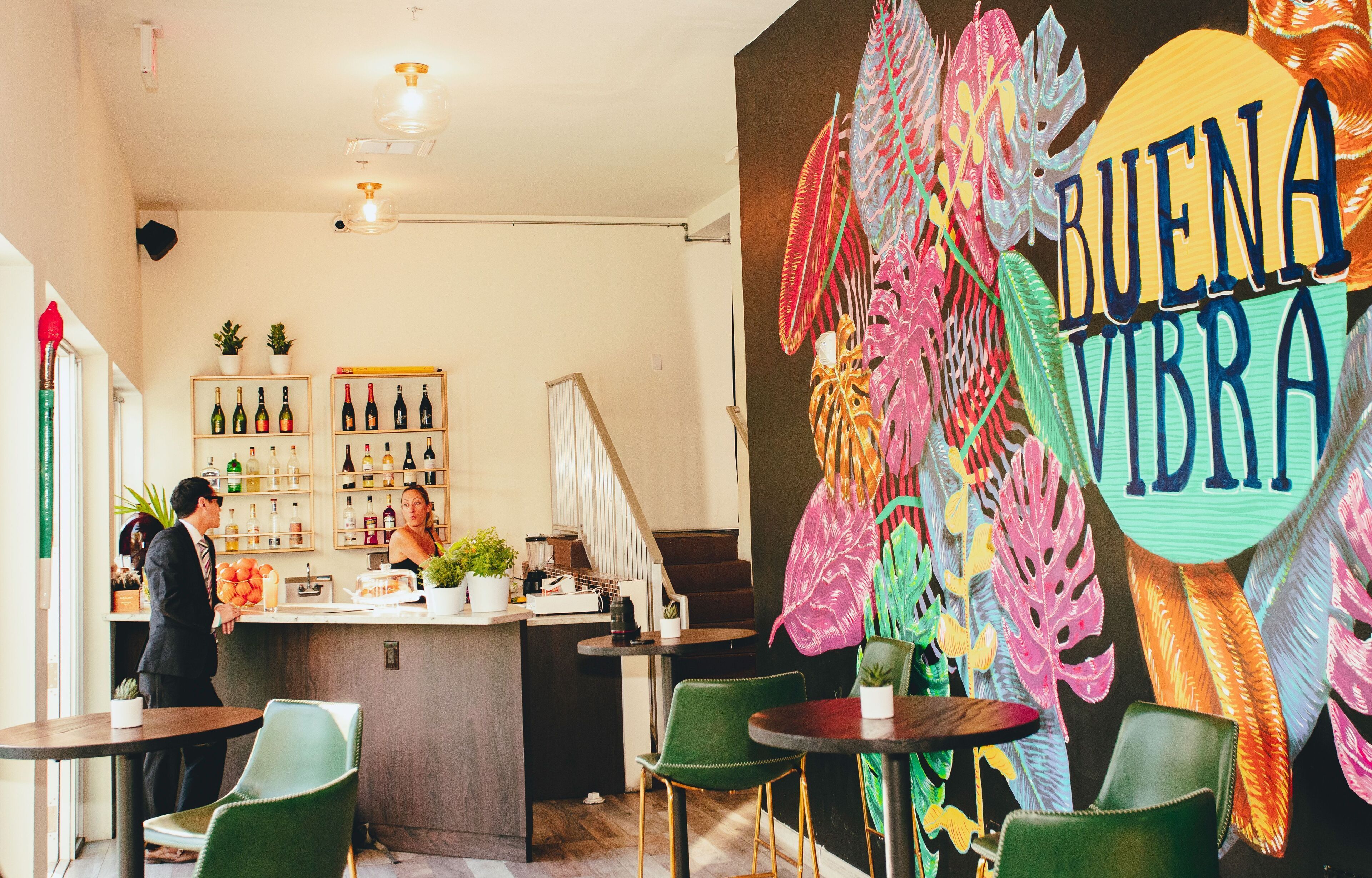 A bar area with a counter, chairs, and a wall with 'BUENA VIBRA' text.