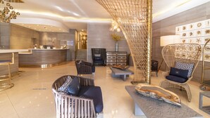 A modern lobby with a reception desk, seating area, and decorative elements. - San Juan Hotel (Miami Beach)