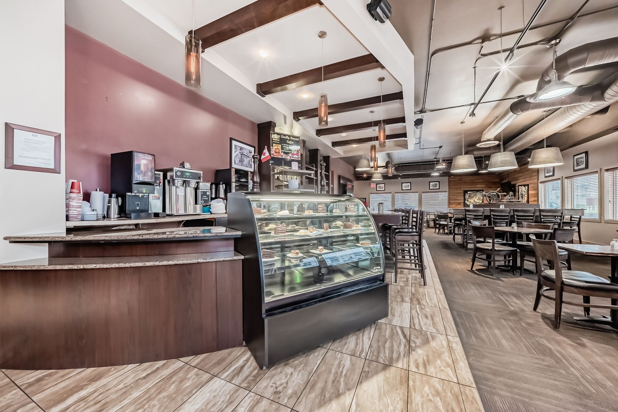 A bakery counter with a display case of pastries, a coffee machine, and a menu board.