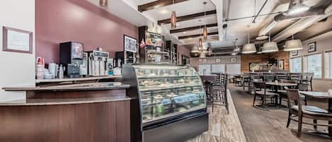 A bakery counter with a display case of pastries, a coffee machine, and a menu board.