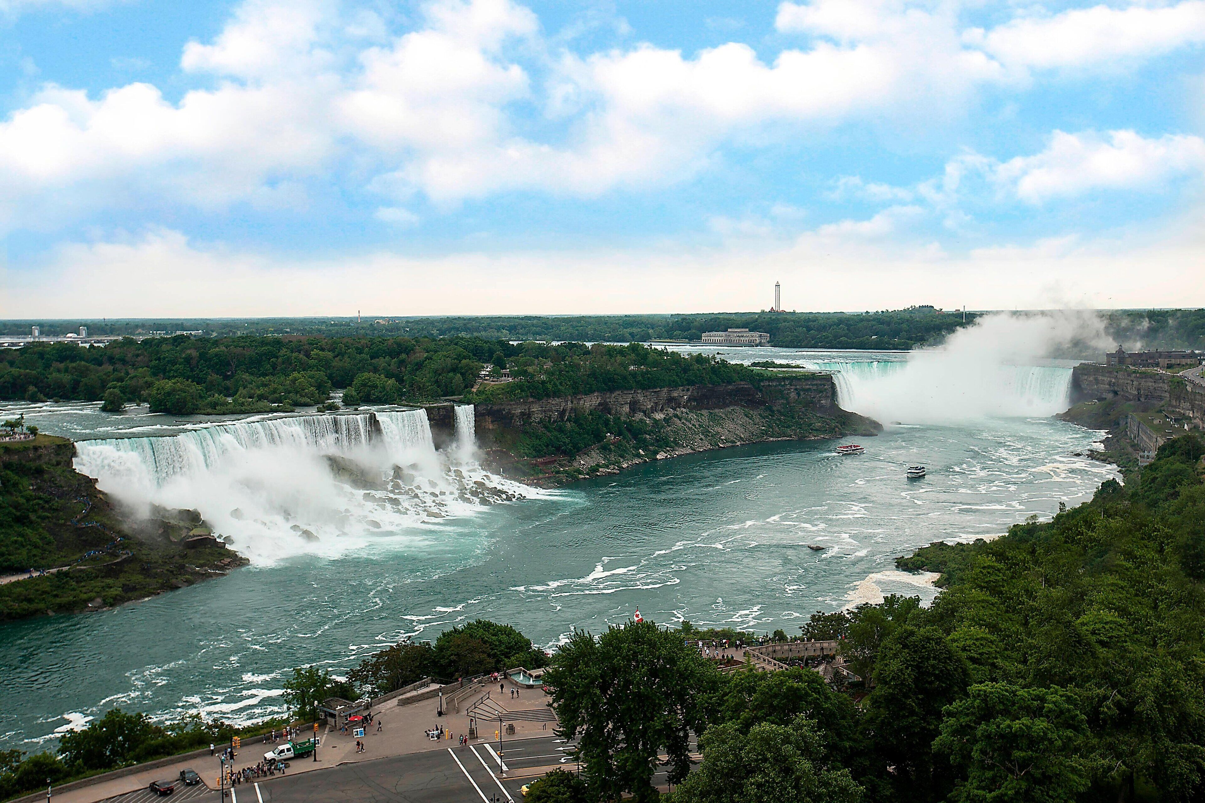 Une grande cascade avec une plateforme d’observation et un bâtiment situé au loin.