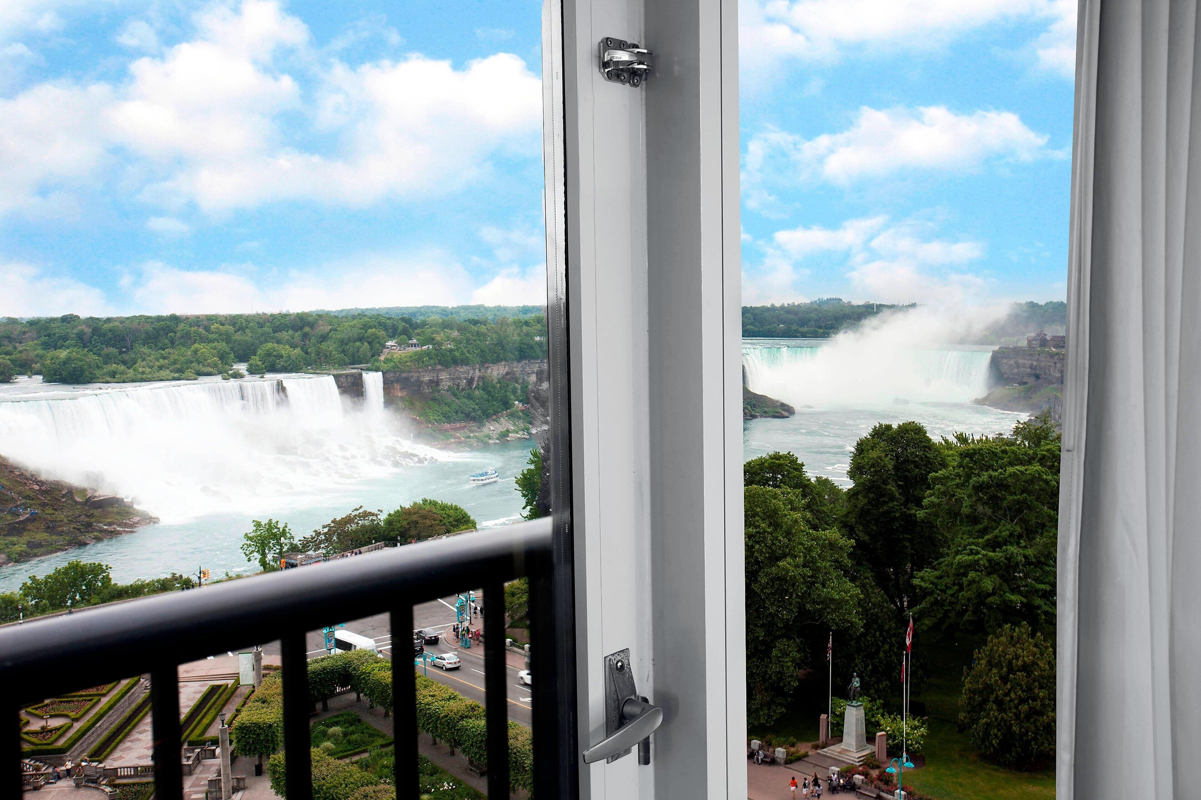 A view of a waterfall from a window, with a statue and greenery visible.