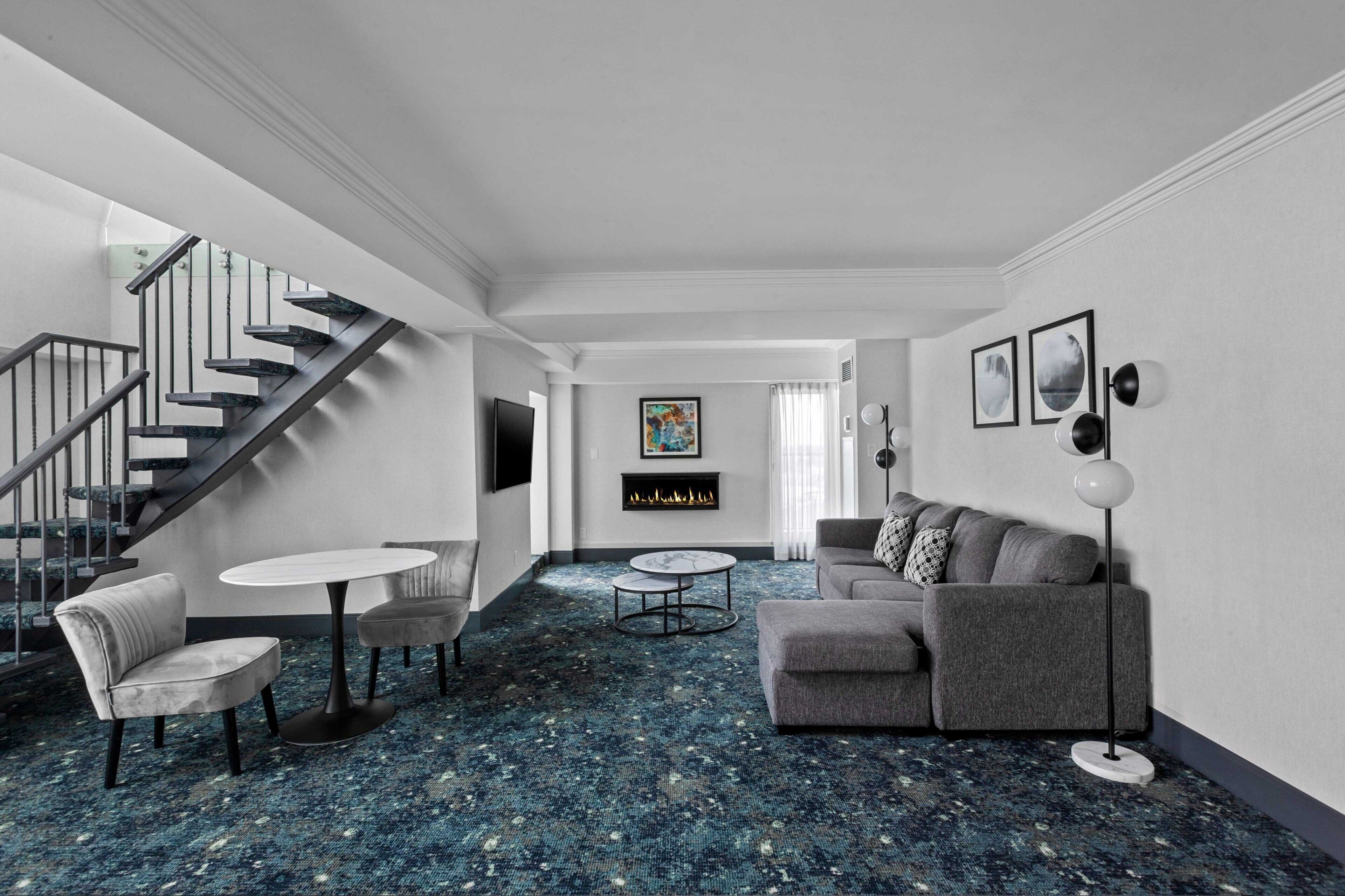 A modern living room with a staircase, a fireplace, a sofa, and a coffee table.