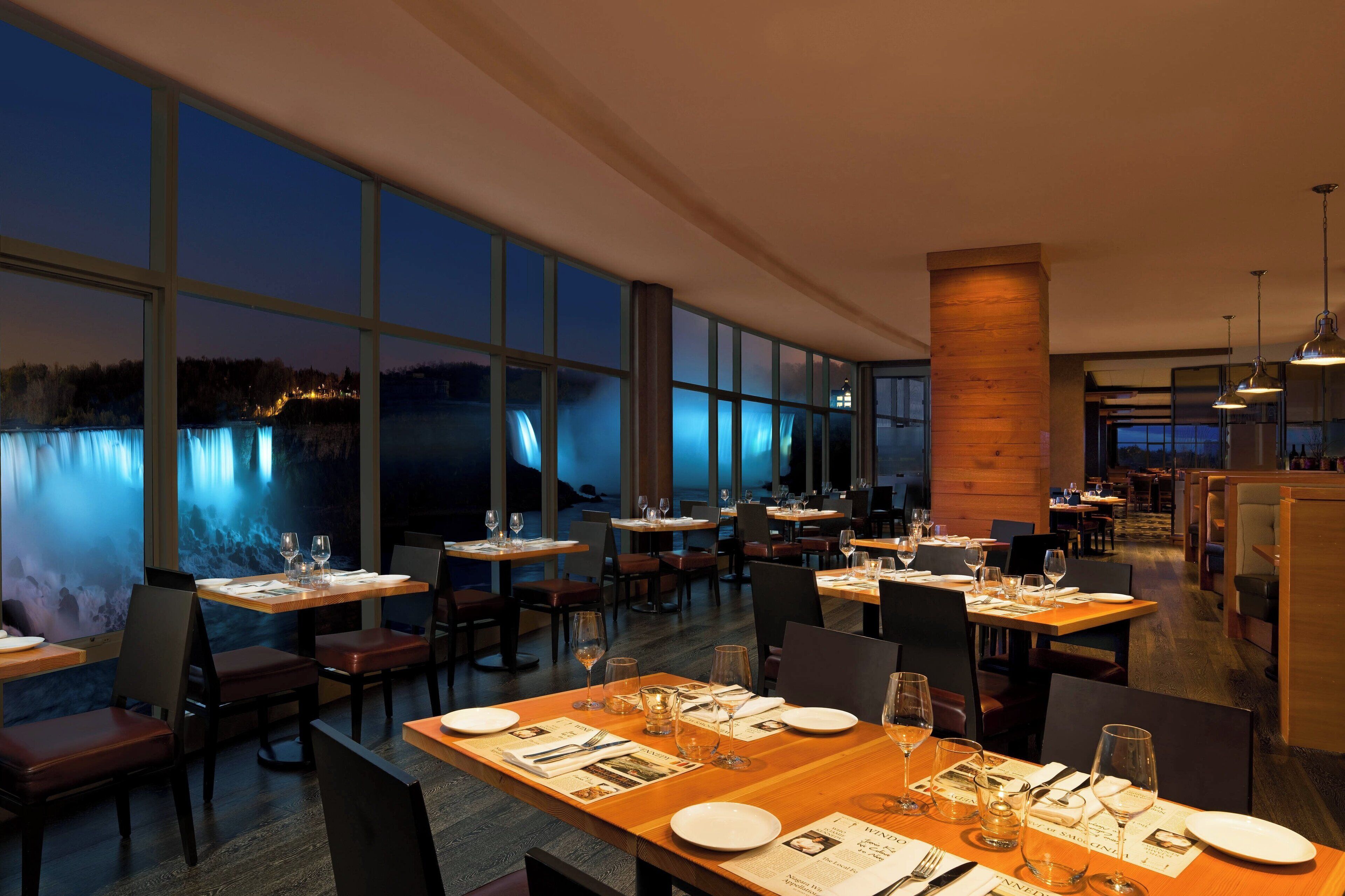 A restaurant with large windows, wooden tables, and chairs.