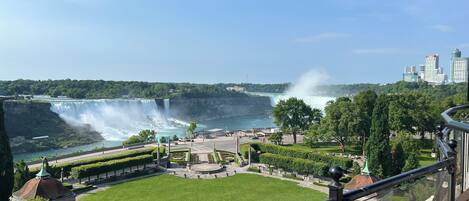 A view of a waterfall, a park with a circular plaza, and a city skyline in the background.