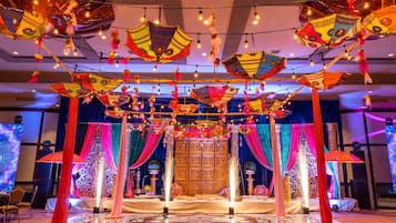 A room with a patterned carpet, draped curtains, and hanging decorative items.