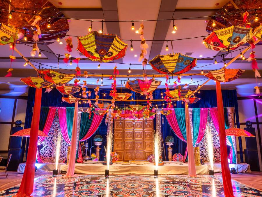 A room with a patterned carpet, draped curtains, and hanging decorative items.