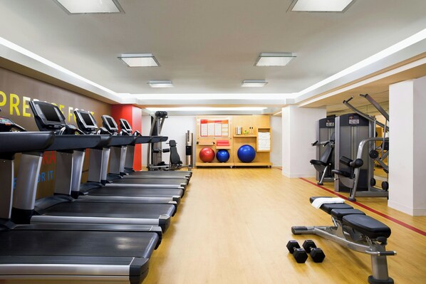 A gym with treadmills, dumbbells, and exercise balls.
