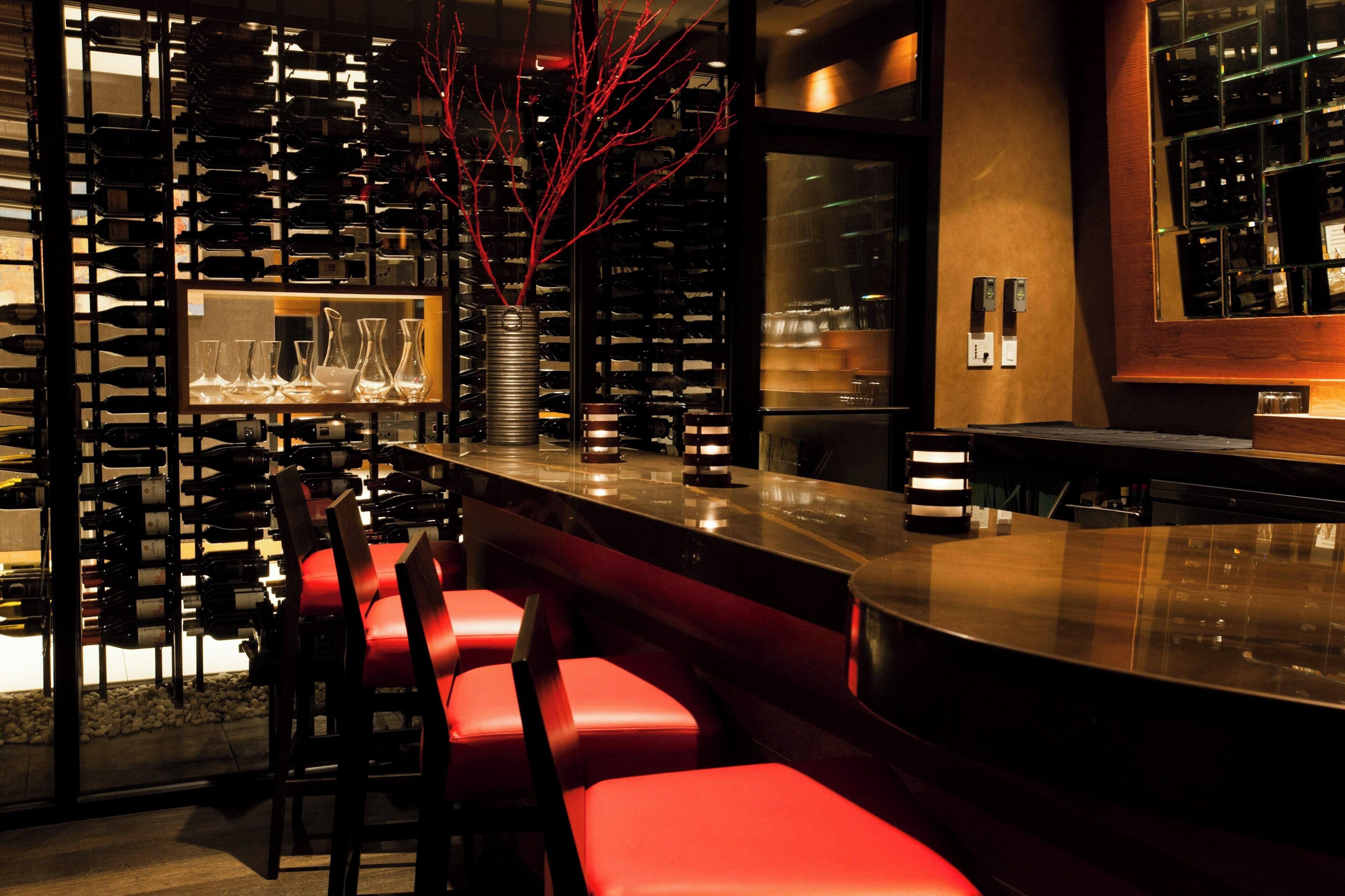 A bar area with a wine rack, red bar stools, and a decorative vase.