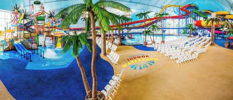 An indoor water park with slides, pools, and lounge chairs.