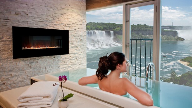 Une femme se détend dans une baignoire, avec vue sur une cascade.