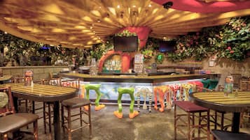 Een bar met een toonbank, krukken en een televisiescherm.