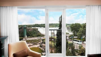 Una habitación con un ventanal que ofrece vistas a una cascada, vegetación y un puente.
