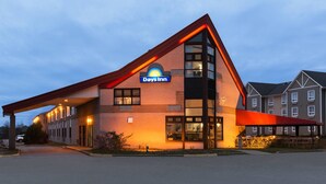 A Days Inn hotel with a modern design, featuring a prominent red roof and a large sign. - Days Inn by Wyndham Trois-Rivieres (Trois-Rivieres)