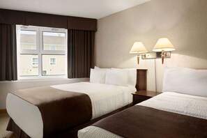 A hotel room with two beds, a window with curtains, and wall-mounted lamps.
