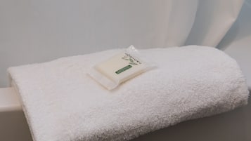 Un asciugamano bianco piegato ordinatamente su una superficie bianca, con una piccola confezione etichettata "Eco-Loc" sopra.