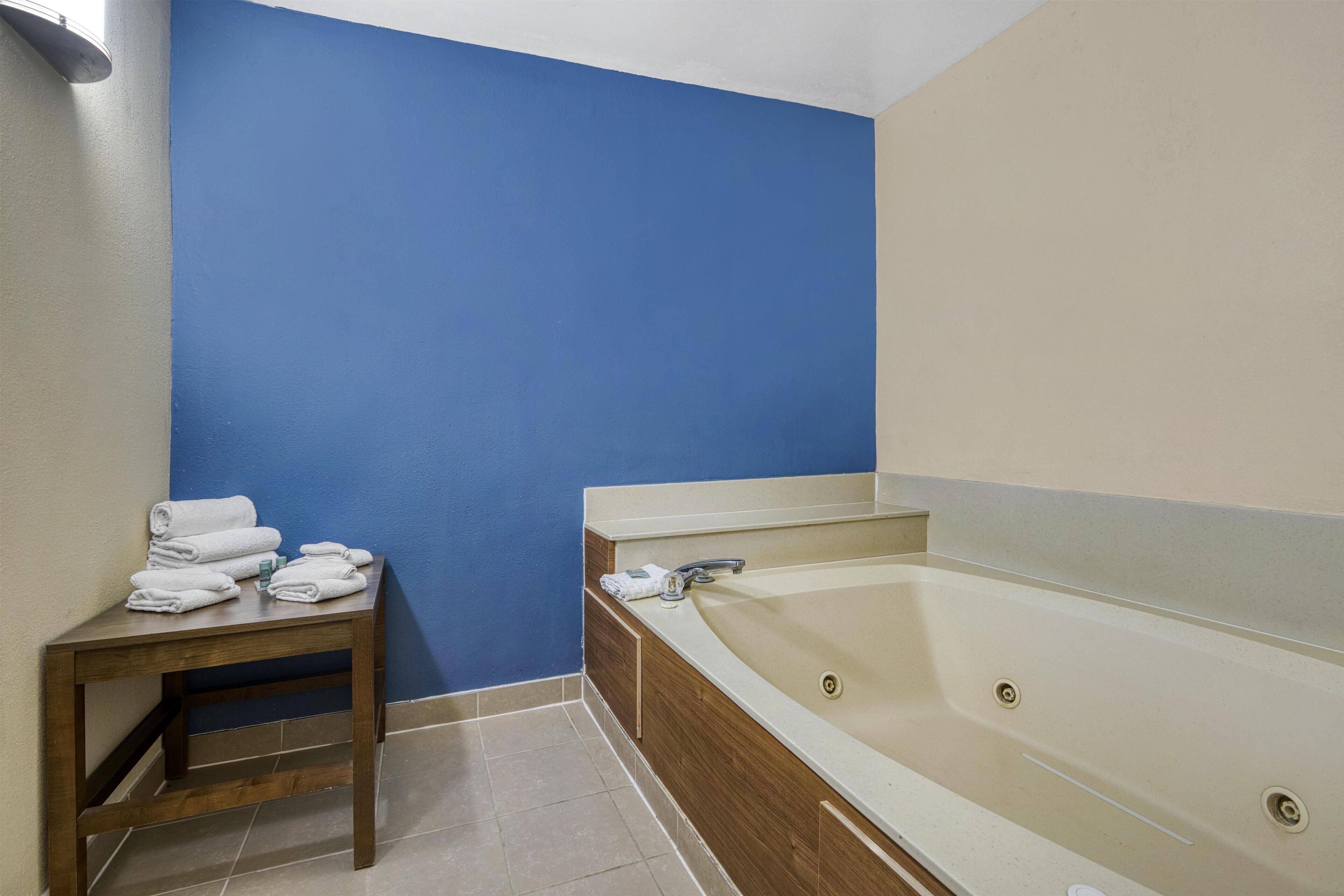 A bathroom with a blue wall, a wooden table with towels, and a bathtub.