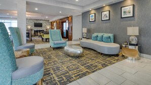 A modern hotel lobby with a seating area featuring sofas and armchairs, a patterned rug, and a television mounted on the wall. - Best Western Fishers/Indianapolis Area (Fishers)