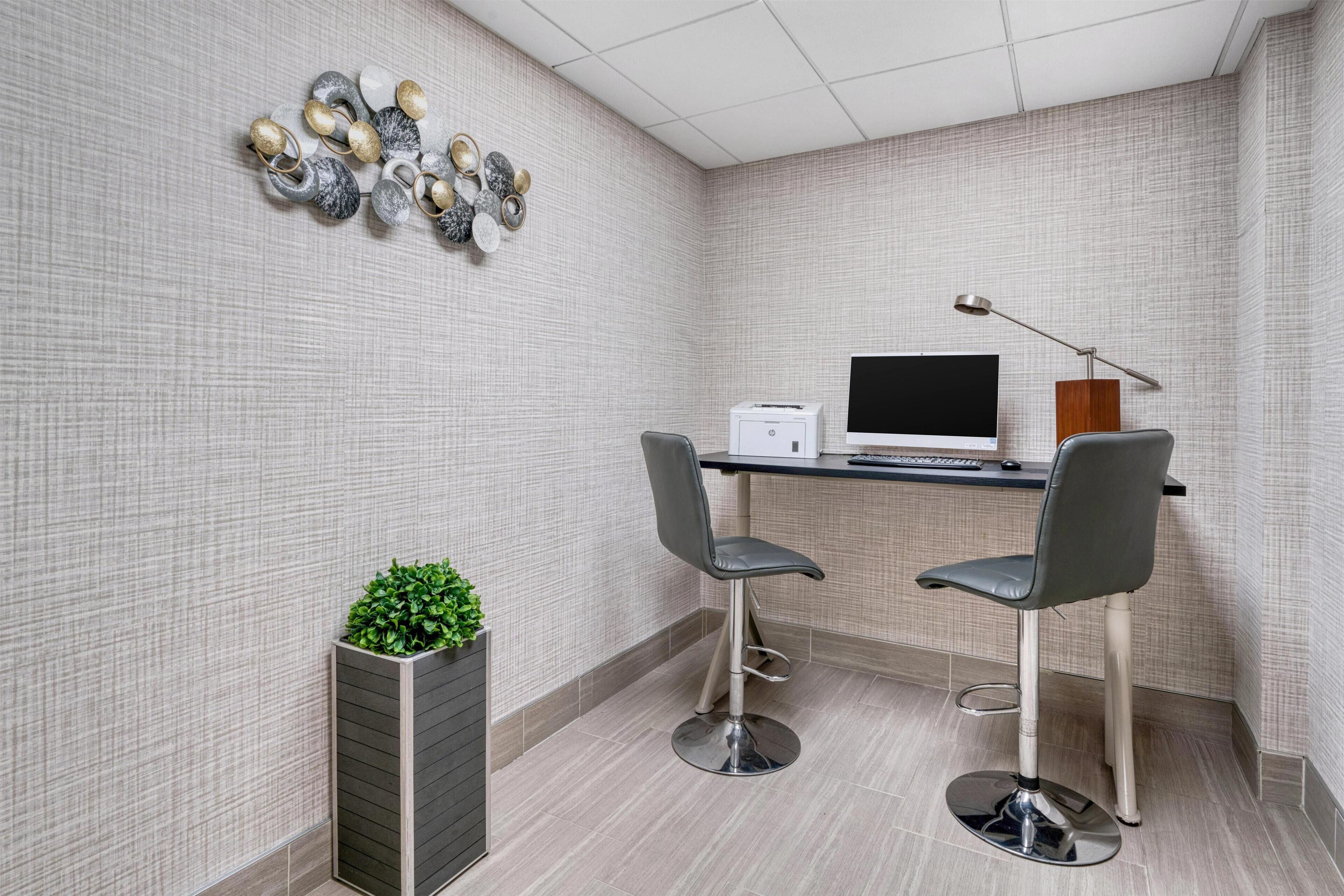 A modern office space with a desk, two chairs, a printer, and decorative wall art.