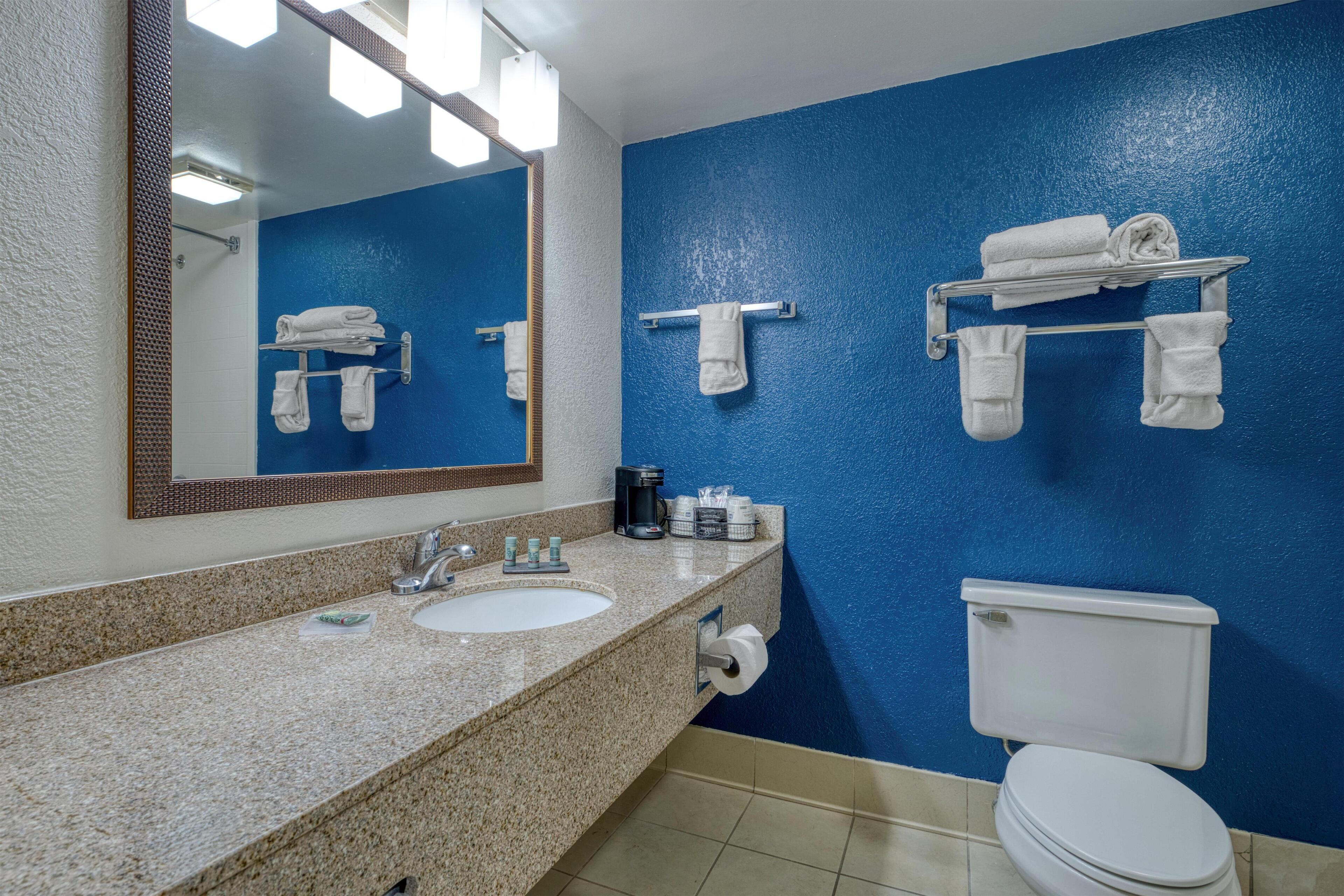 A bathroom with a blue wall, a sink with a mirror, and a toilet.