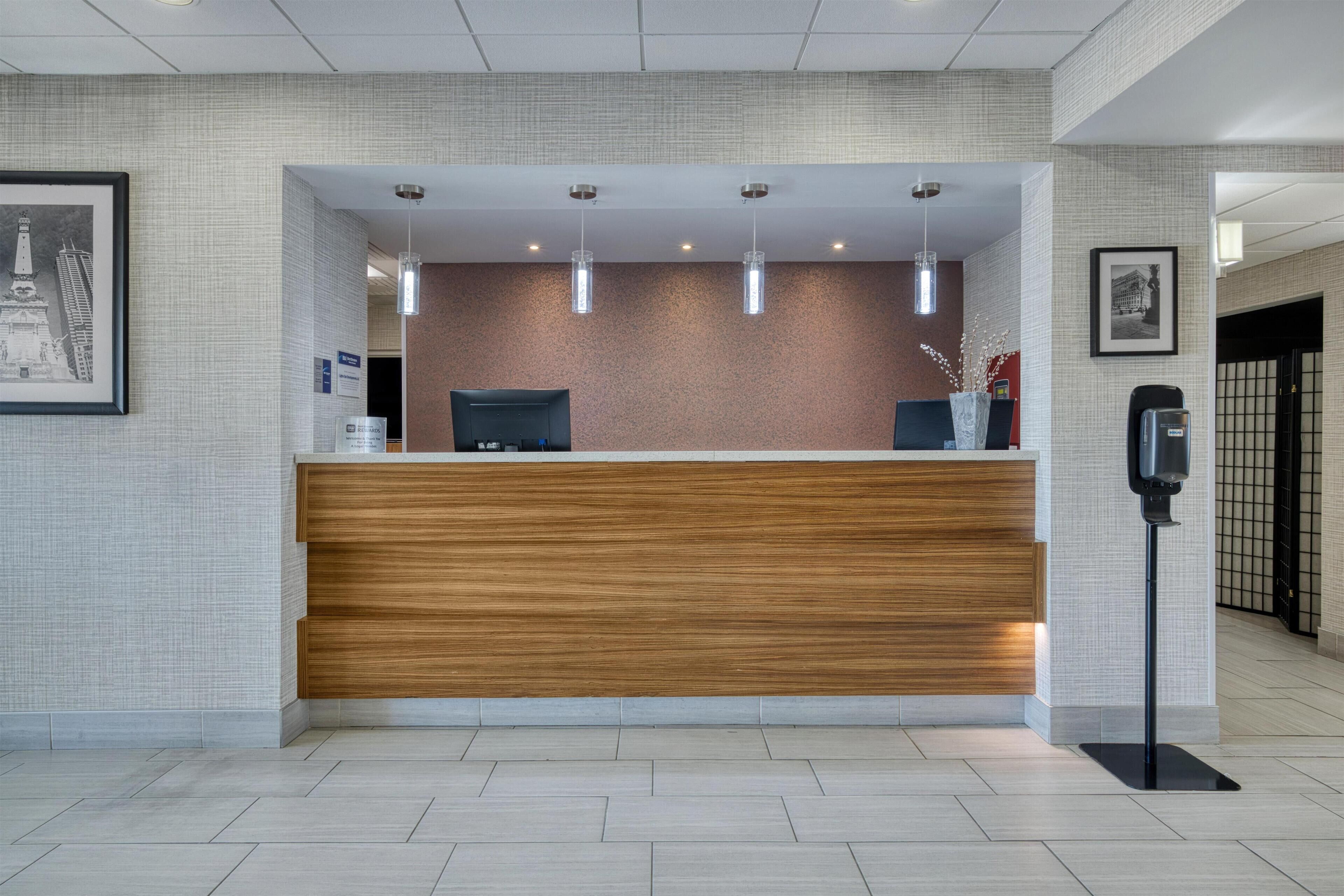 Un comptoir d’accueil avec un revêtement en bois, une chaise de bureau noire et des luminaires suspendus.
