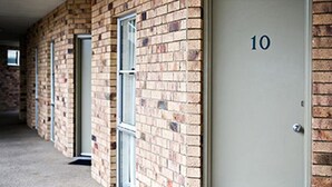 A hallway with brick walls and doors numbered 10. - Gympie Muster Inn (Gympie)