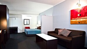 A modern hotel room with a single bed, a sofa, a coffee table, and a desk. - Gympie Muster Inn (Gympie)