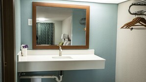 Een badkamer met een wit wastafel, een spiegel en een handdoekhouder.