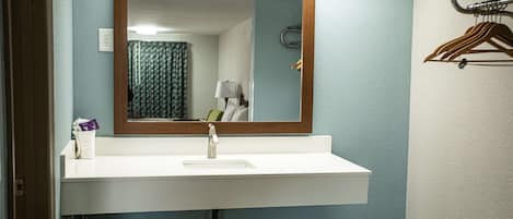 A bathroom with a white sink, a mirror, and a towel rack.