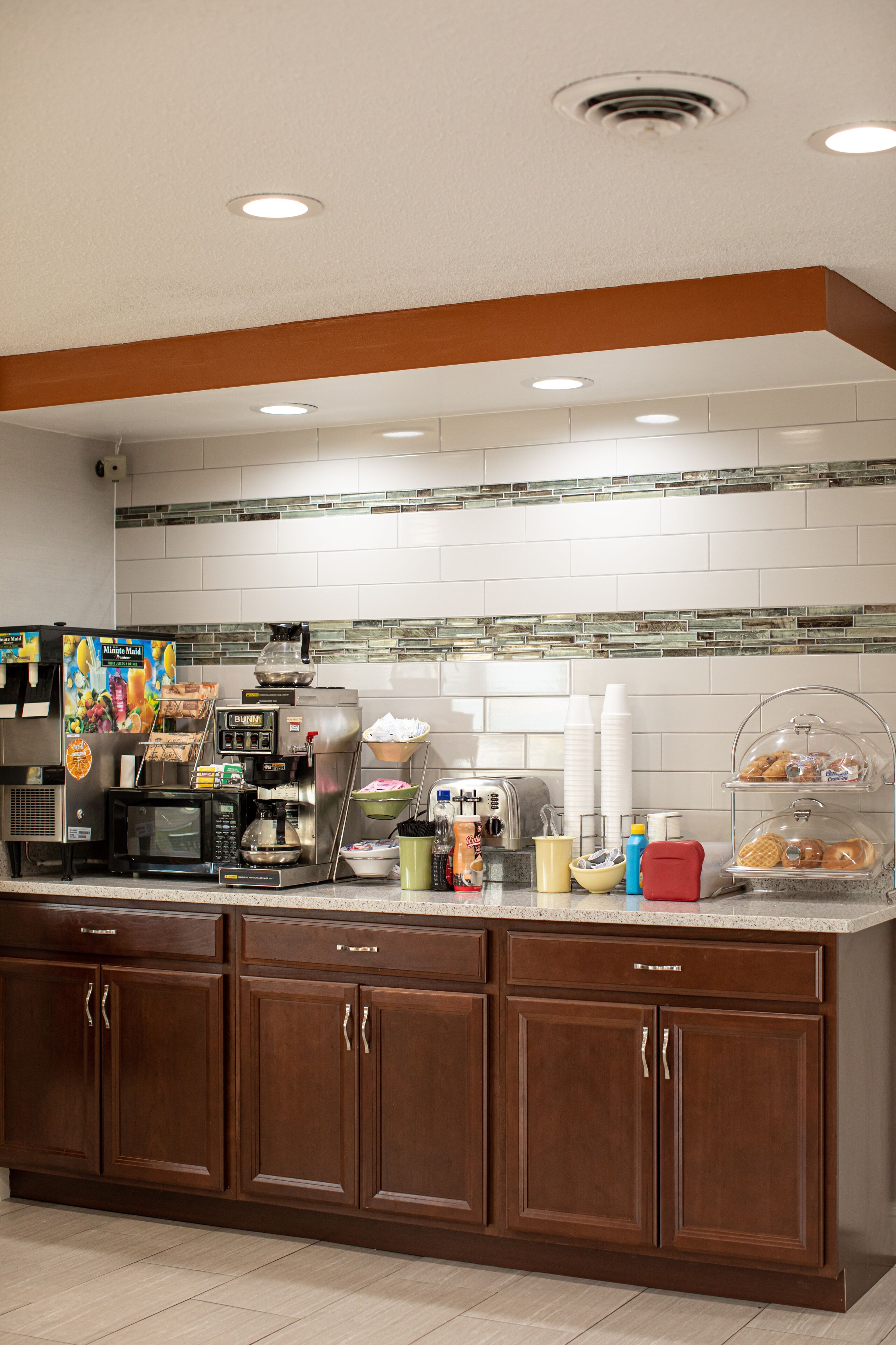 A kitchen area with a coffee machine, a microwave, and a bread display.