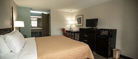 Une chambre d’hôtel équipée d’un lit, d’un bureau, d’une chaise, d’une télévision et d’un four à micro-ondes.